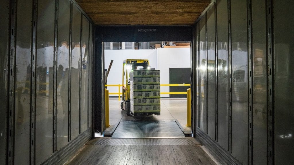 A forklift truck carries a pallet into a storage unit